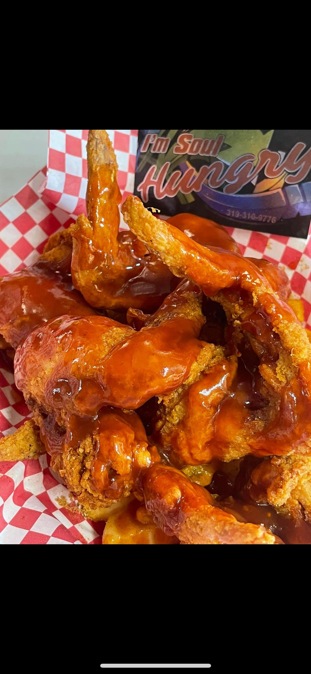 Whole wings drenched in sauce over seasoned potatoes